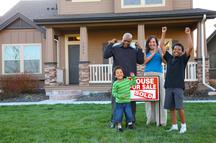 Family with sold sign celebrating home purchase